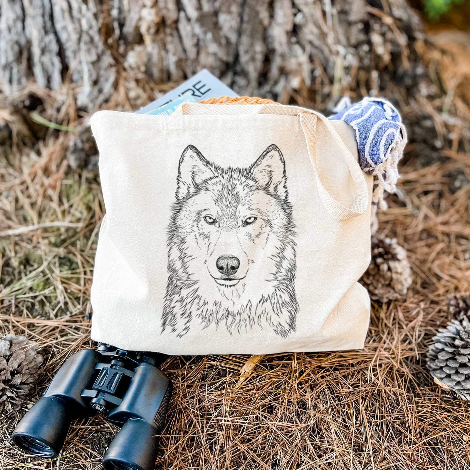 Natural canvas tote bag printed with a detailed black ink portrait of a grey wolf facing forward.