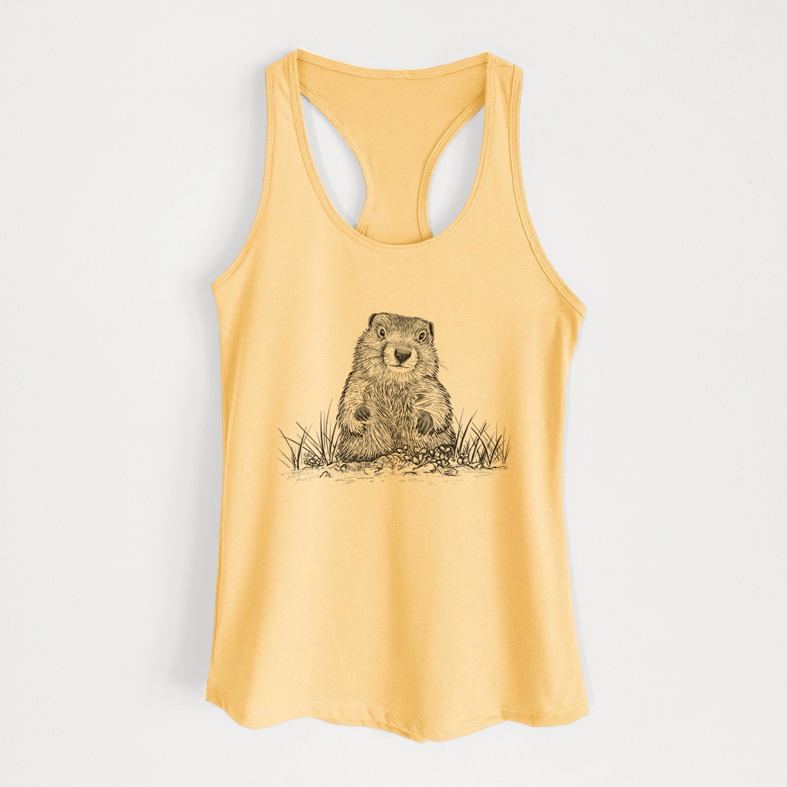 Banana cream women's racerback tank top laid flat, printed with a black ink illustration of a groundhog peeking out of its burrow among grass.