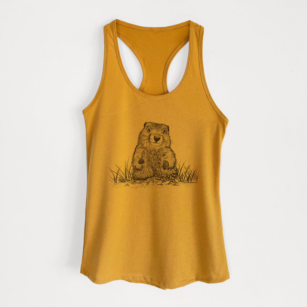 Gold women's racerback tank top laid flat, printed with a black ink illustration of a groundhog peeking out of its burrow among grass.