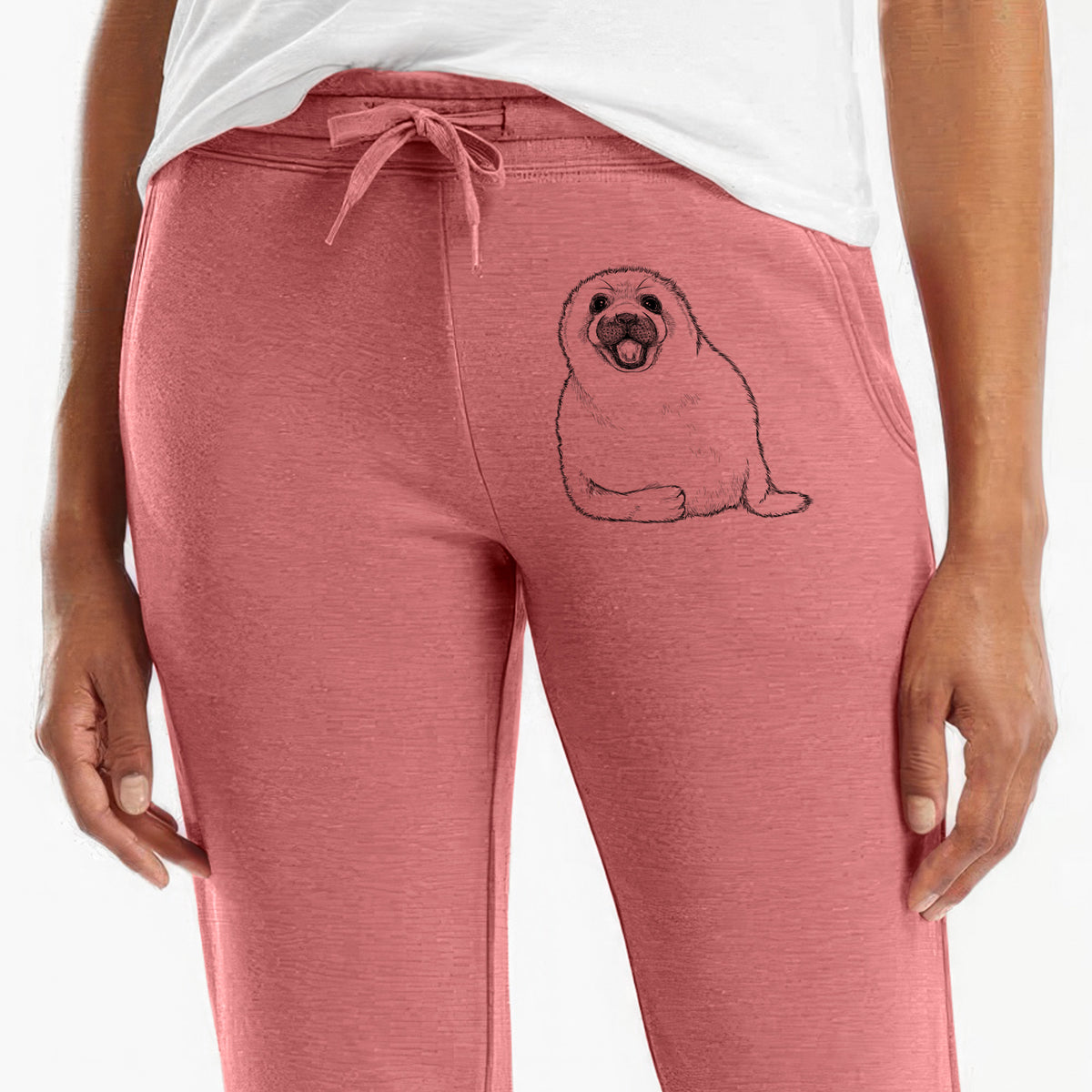 Front of dusty rose Cali Wave sweatpants, printed with a black ink illustration of a smiling harp seal pup lying down on the leg.