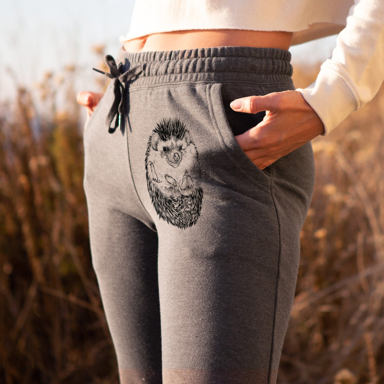 Front of dusty rose Cali Wave sweatpants, printed with a detailed black ink illustration of a hedgehog curled up and facing forward on the leg.