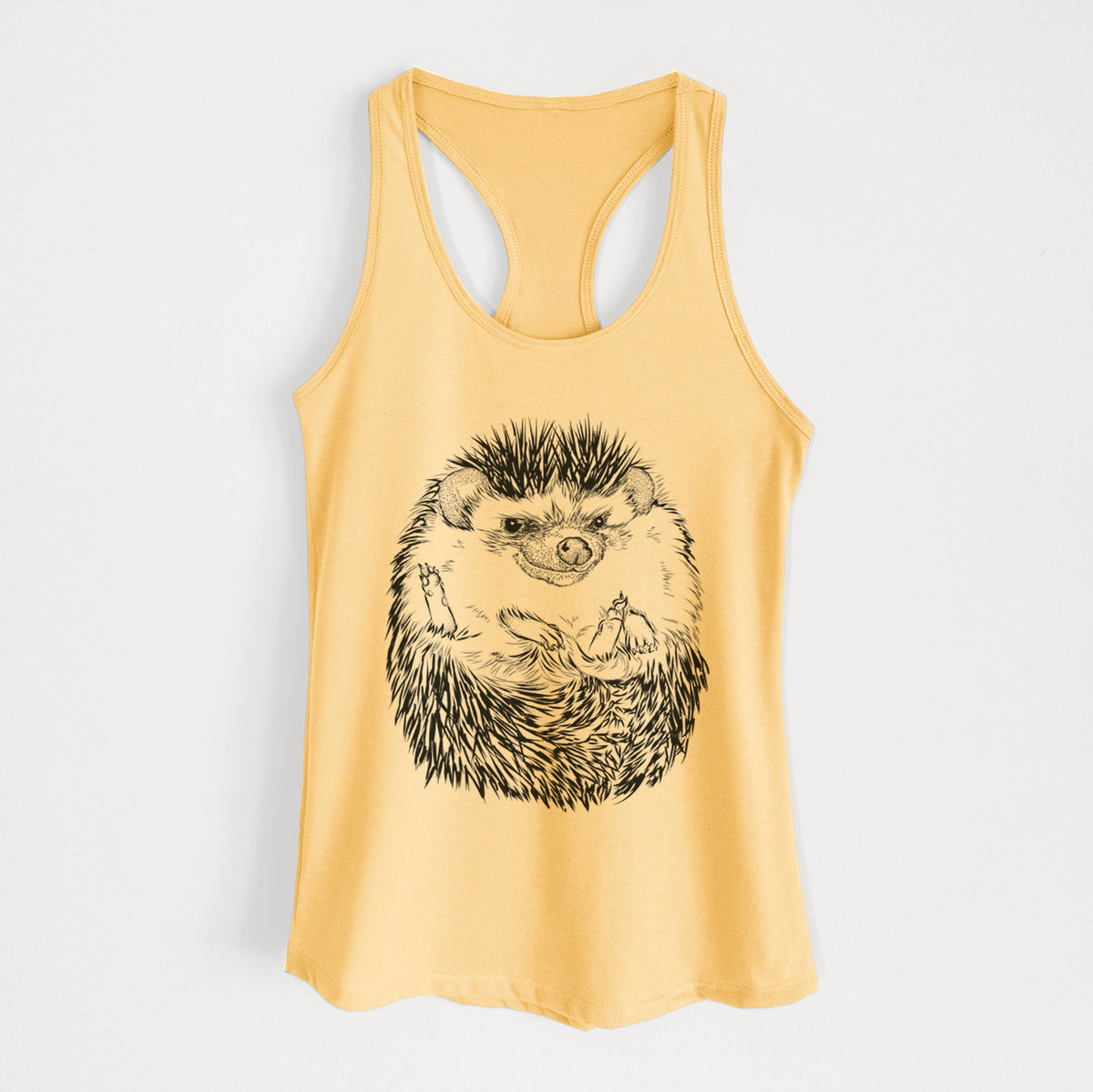 Banana cream women's racerback tank top laid flat, printed with a detailed black ink illustration of a hedgehog curled up and facing forward.