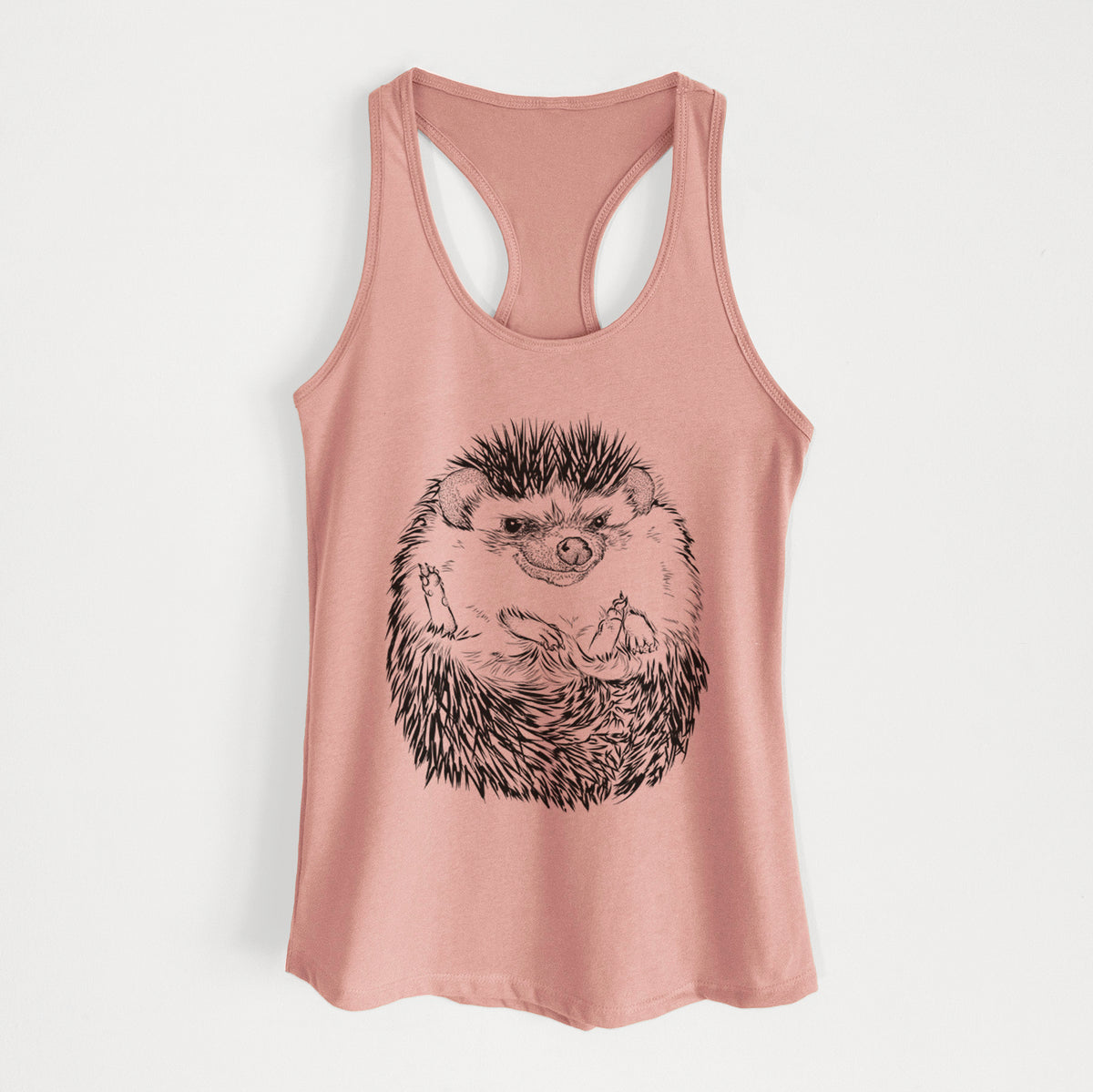 Desert pink women's racerback tank top laid flat, printed with a detailed black ink illustration of a hedgehog curled up and facing forward.