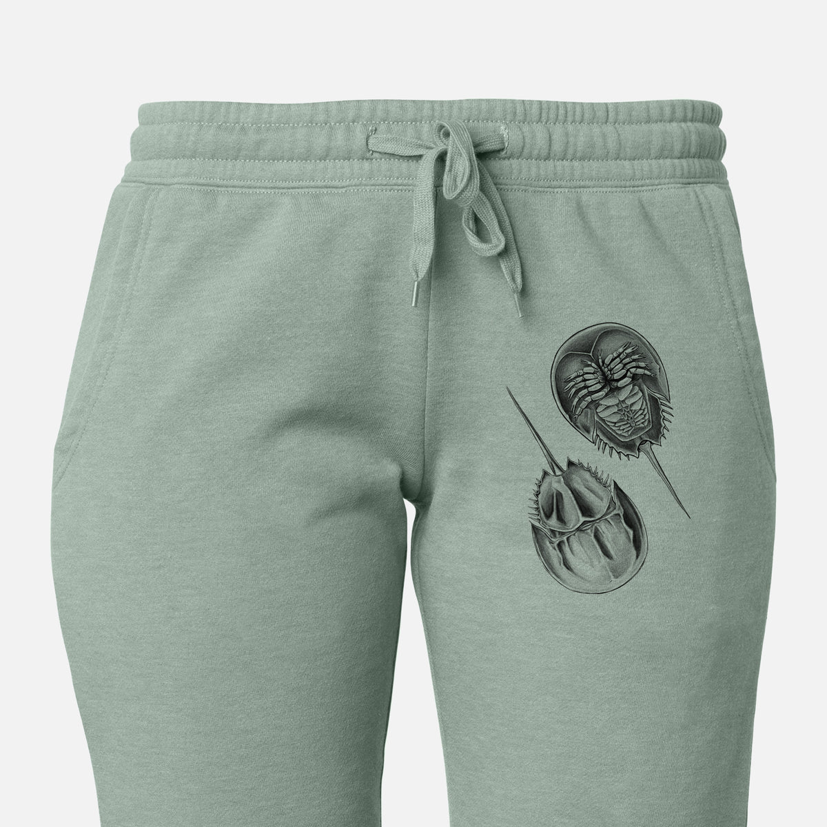 Front of sage green Cali Wave sweatpants, printed with a detailed black ink illustration of two horseshoe crabs on the leg.