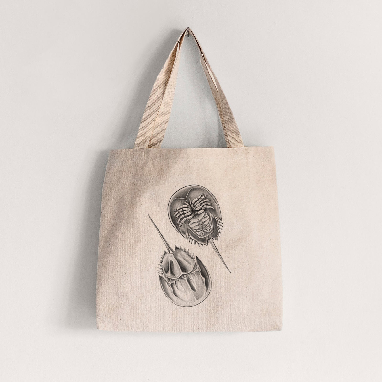 Natural canvas tote bag printed with a detailed black ink illustration of two horseshoe crabs.