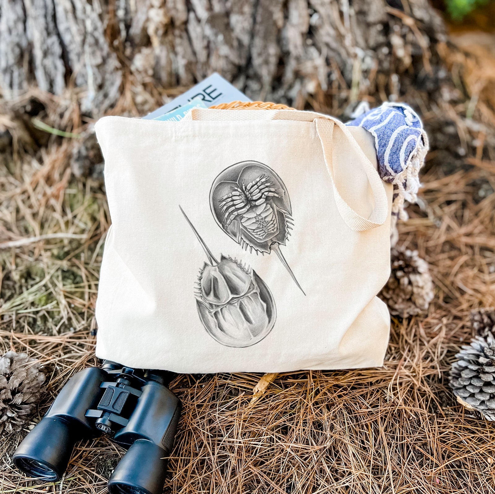 Natural canvas tote bag printed with a detailed black ink illustration of two horseshoe crabs.