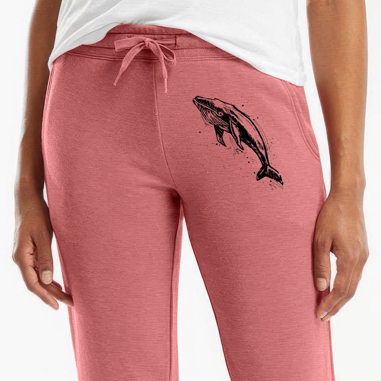 Front of dusty rose Cali Wave sweatpants, printed with a black ink illustration of a humpback whale diving, with ink splatters on the leg.