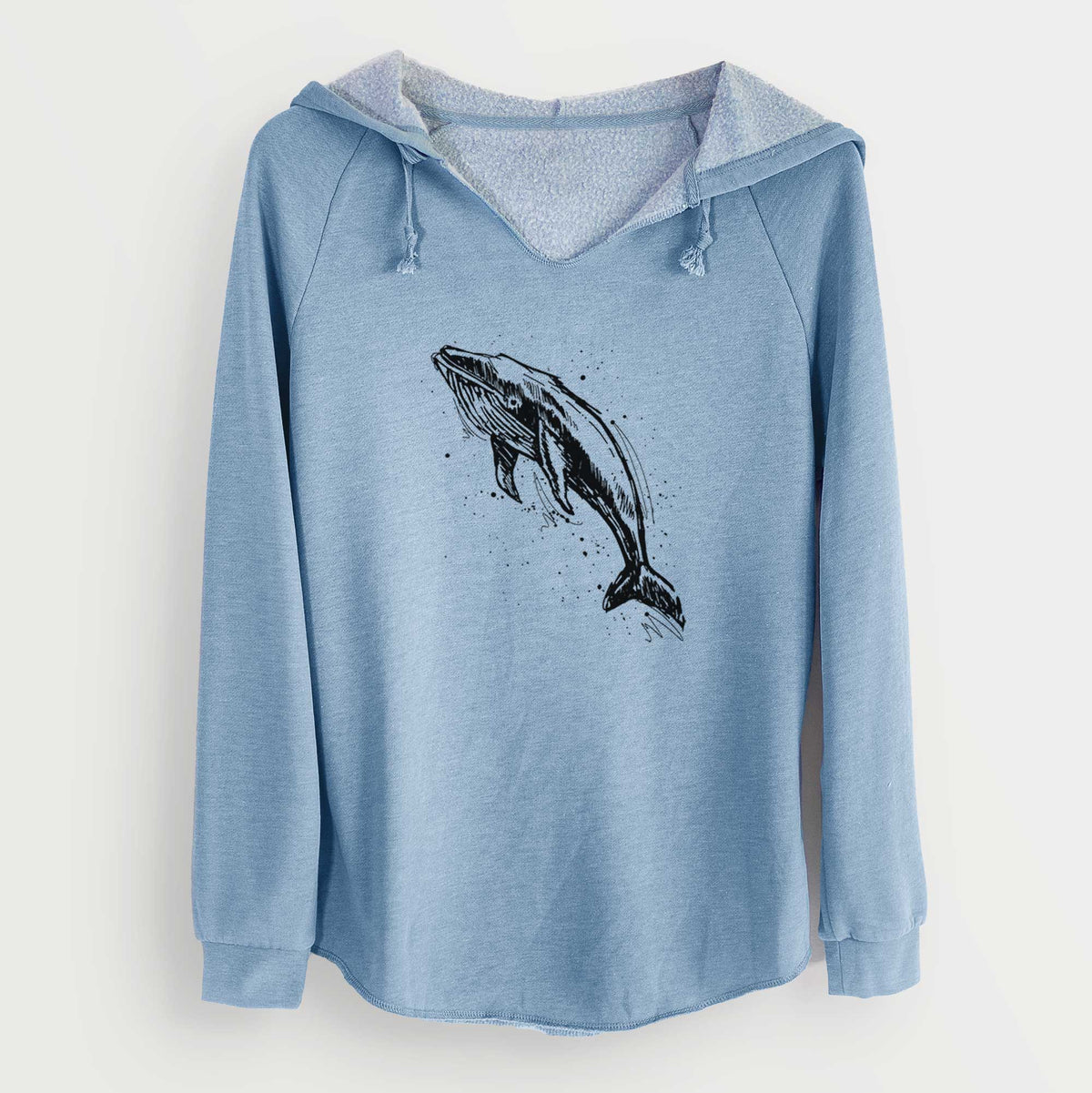 Misty blue women's Cali Wave hooded sweatshirt laid flat, printed with a black ink illustration of a humpback whale diving, with ink splatters.