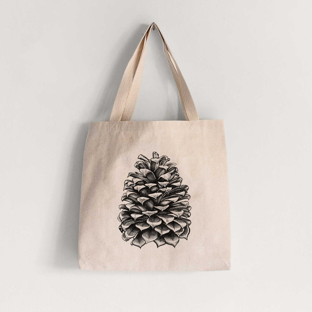 Natural canvas tote bag printed with a detailed black ink illustration of a large Jeffrey pine cone.