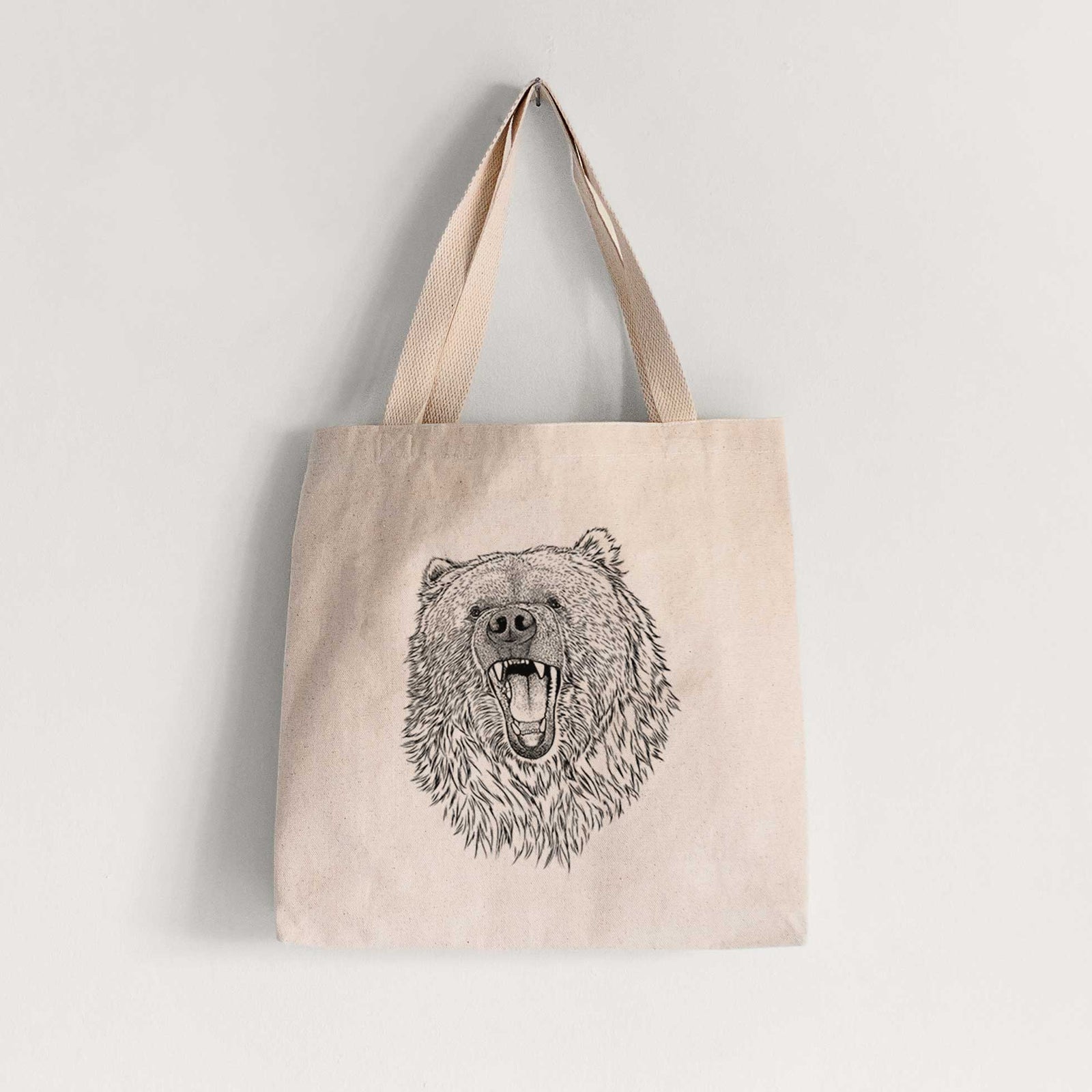 Natural canvas tote bag printed with a detailed black ink portrait of a roaring Kodiak bear facing forward.