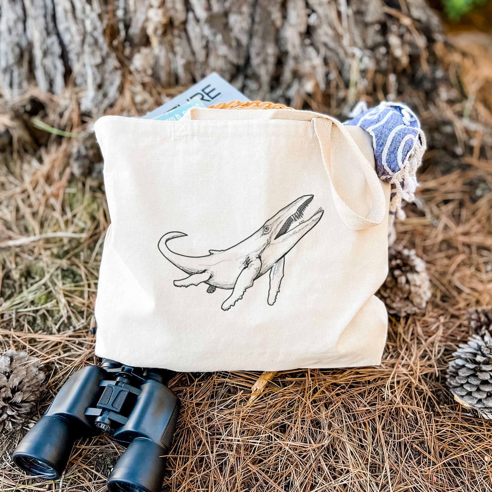 Natural canvas tote bag printed with a black ink illustration of a Kronosaurus marine reptile swimming.