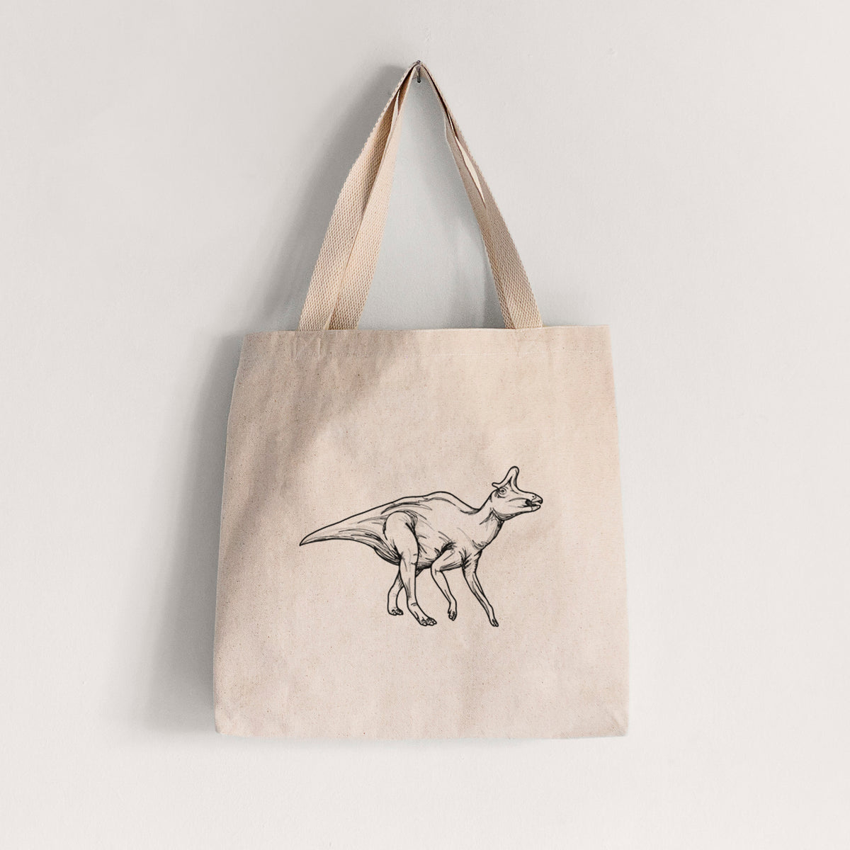 Natural canvas tote bag printed with a black ink illustration of a crested Lambeosaurus walking.
