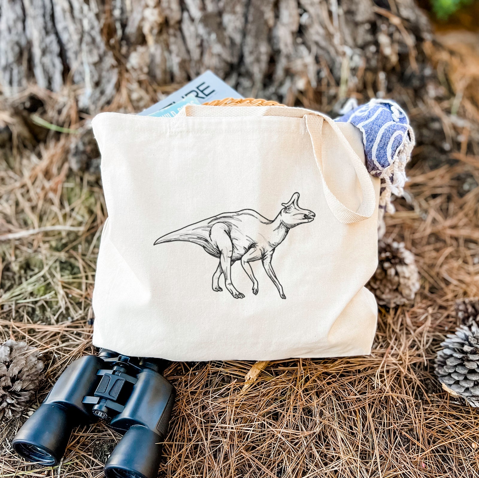 Natural canvas tote bag printed with a black ink illustration of a crested Lambeosaurus walking.