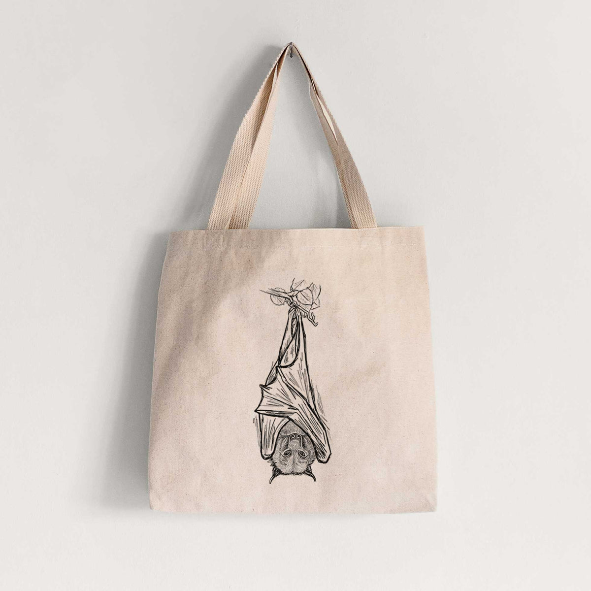Natural canvas tote bag printed with a black ink illustration of a large flying fox bat hanging upside down with its wings wrapped around it.