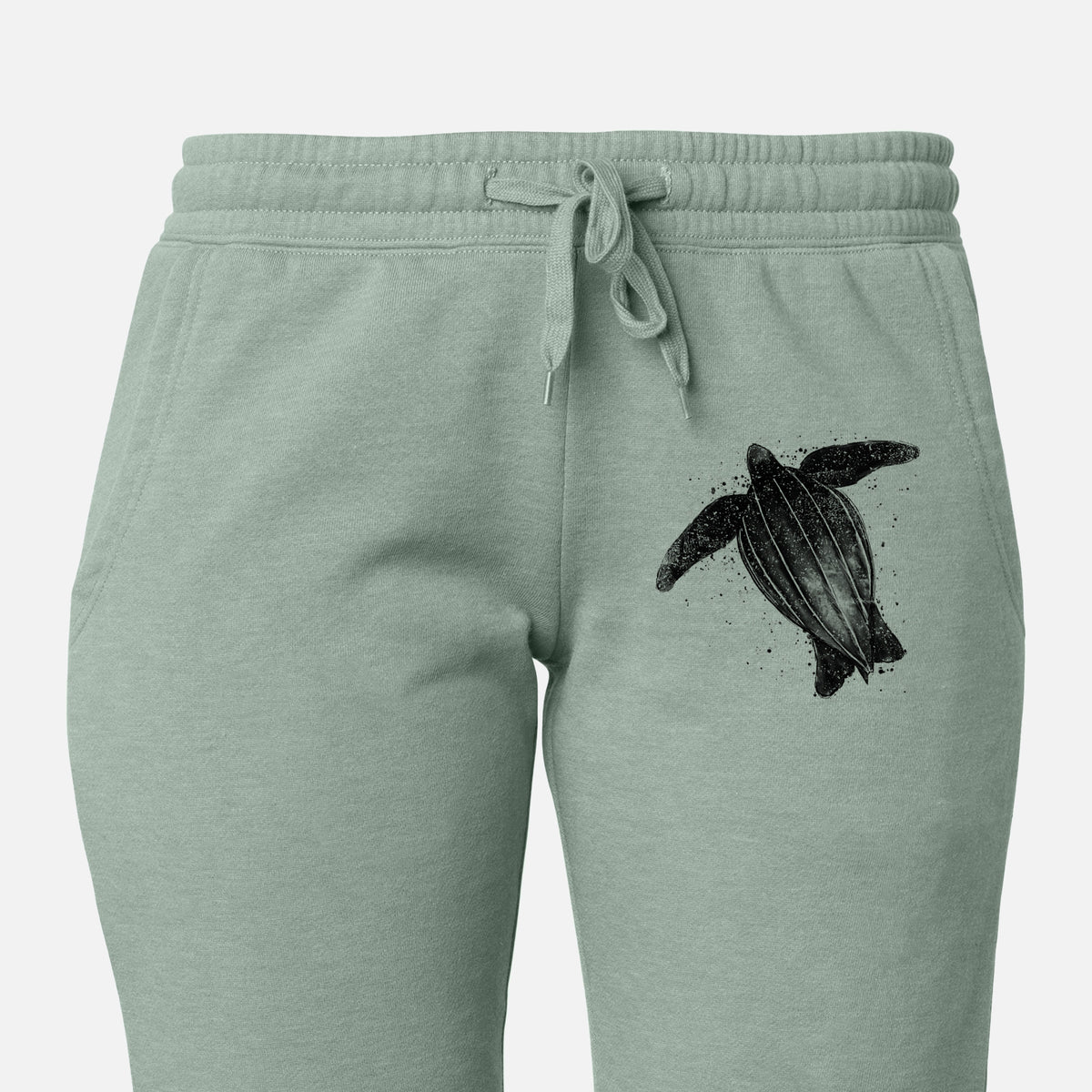Front of sage green Cali Wave sweatpants, printed with a black ink illustration of a leatherback sea turtle swimming, with ink splatters on the leg.