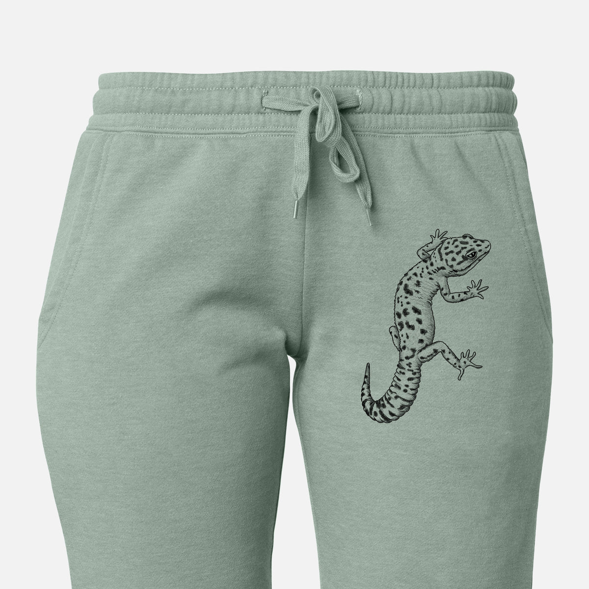 Front of sage green Cali Wave sweatpants, printed with a detailed black ink illustration of a spotted leopard gecko climbing on the leg.