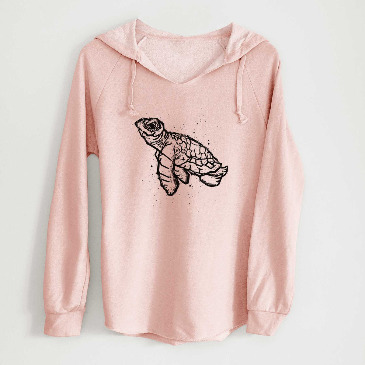 Blush pink women's Cali Wave hooded sweatshirt laid flat, printed with a black linocut-style illustration of a baby sea turtle with a patterned shell and ink splatters.