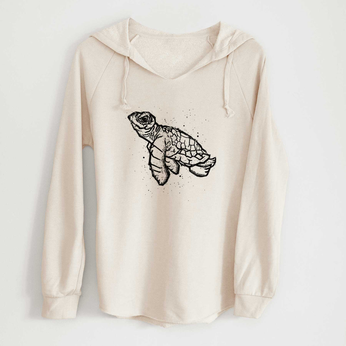Bone cream women's Cali Wave hooded sweatshirt laid flat, printed with a black linocut-style illustration of a baby sea turtle with a patterned shell and ink splatters.