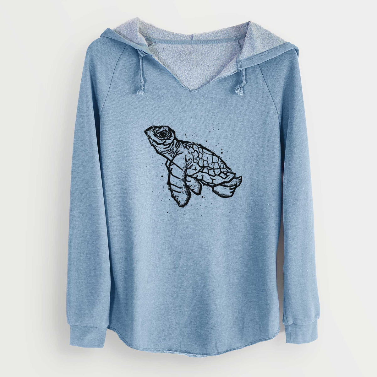 Misty blue women's Cali Wave hooded sweatshirt laid flat, printed with a black linocut-style illustration of a baby sea turtle with a patterned shell and ink splatters.