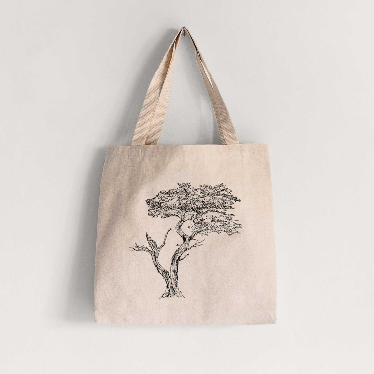 Natural canvas tote bag printed with a black ink illustration of the windswept Lone Cypress tree on a rocky outcrop.