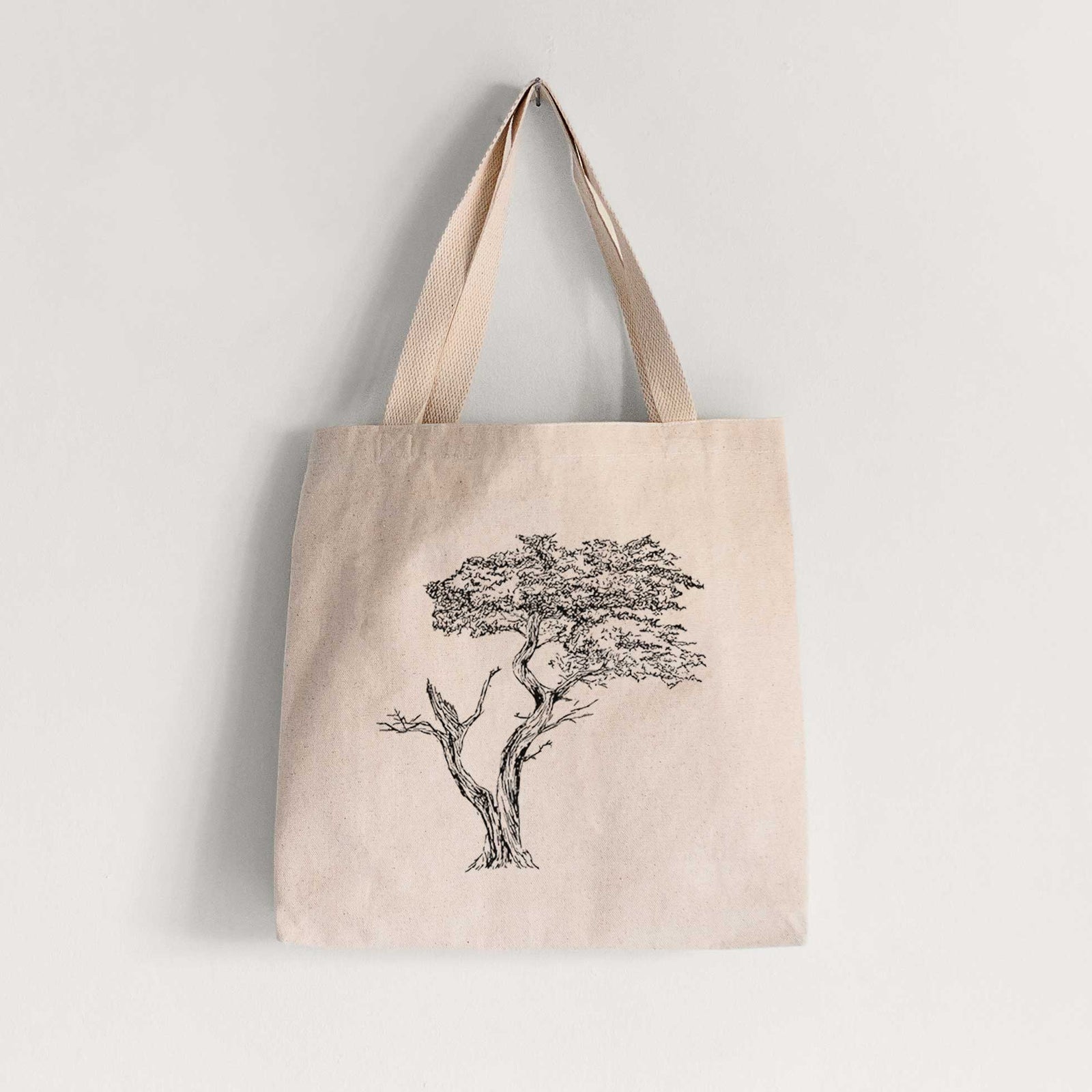 Natural canvas tote bag printed with a black ink illustration of the windswept Lone Cypress tree on a rocky outcrop.