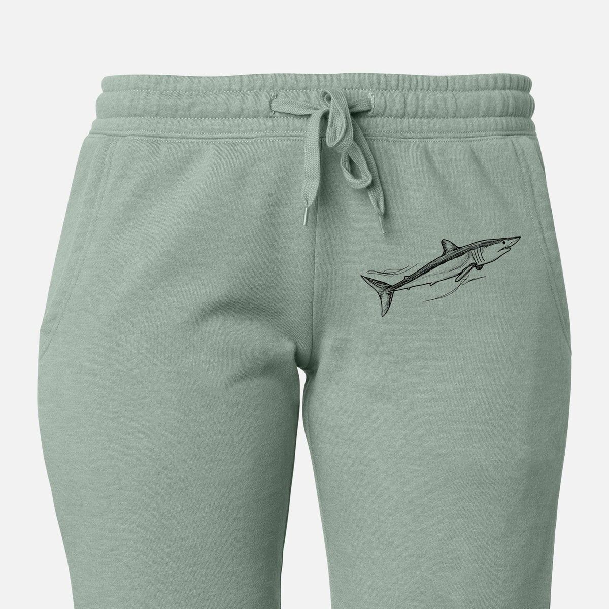Front of sage green Cali Wave sweatpants, printed with a black ink illustration of a mako shark swimming on the leg.