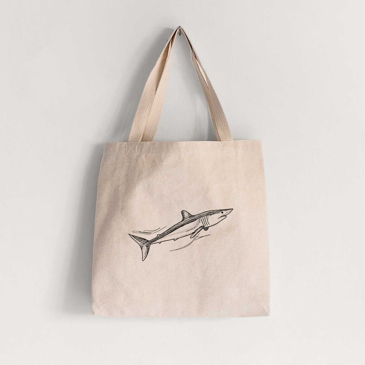 Natural canvas tote bag printed with a black ink illustration of a mako shark swimming.