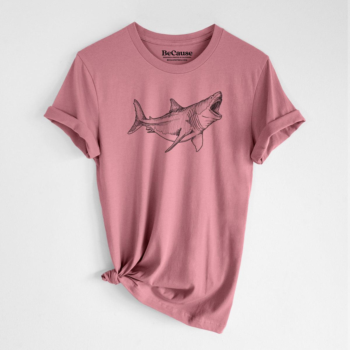 Mauve pink lightweight cotton t-shirt laid flat with the sleeves rolled, printed with a black ink illustration of a megalodon shark with its jaws open.