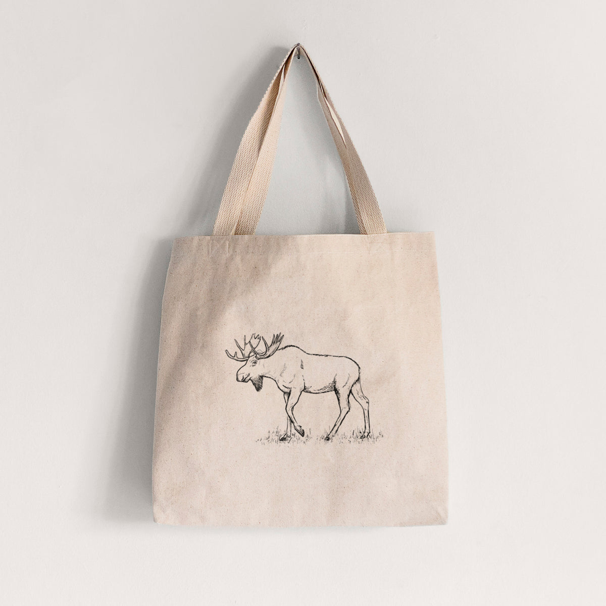 Natural canvas tote bag printed with a black ink illustration of a bull moose with broad antlers walking.