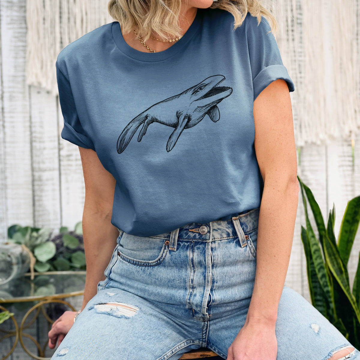 Woman wearing a steel blue lightweight cotton t-shirt printed with a black ink illustration of a Mosasaur swimming.