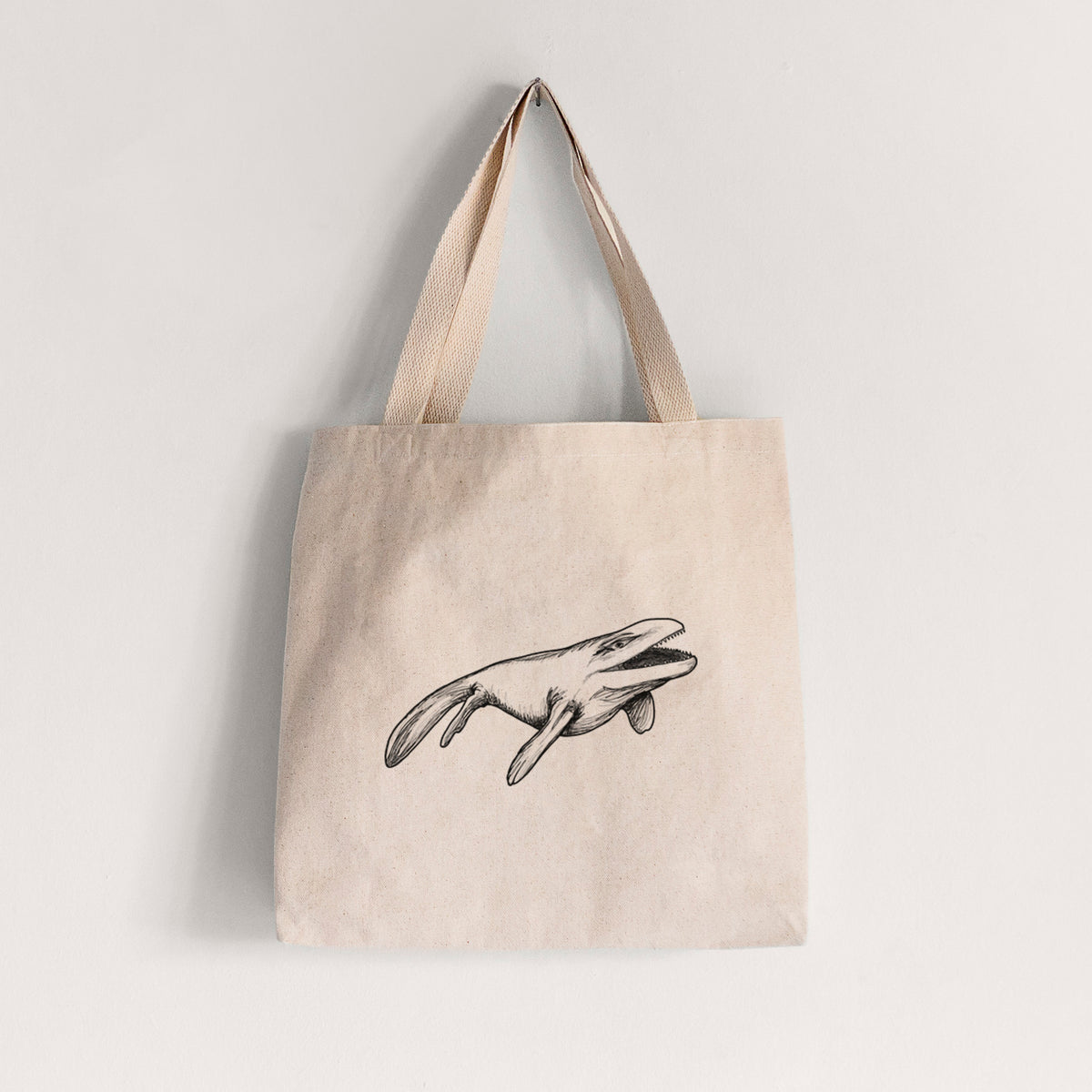 Natural canvas tote bag printed with a black ink illustration of a Mosasaur swimming.