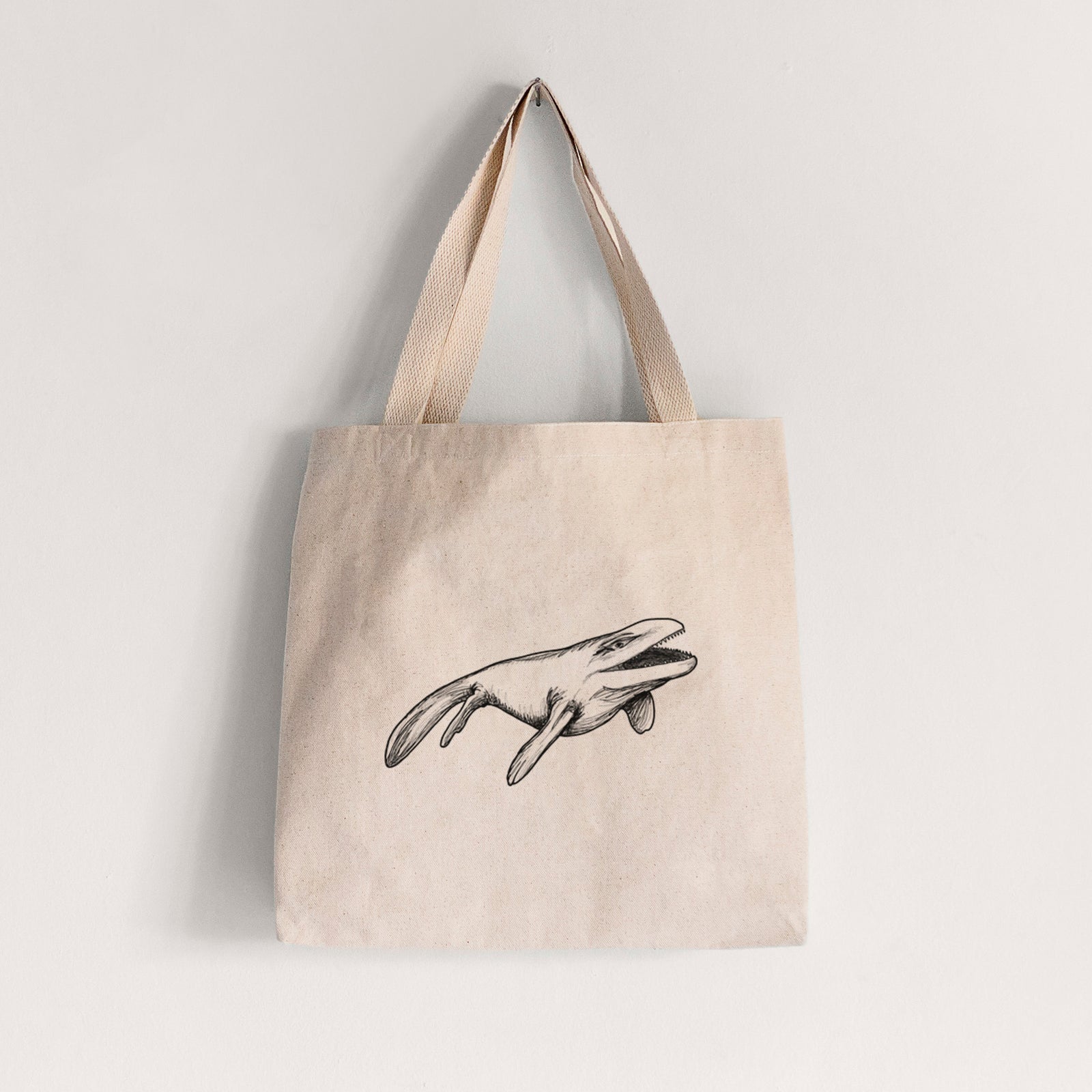 Natural canvas tote bag printed with a black ink illustration of a Mosasaur swimming.