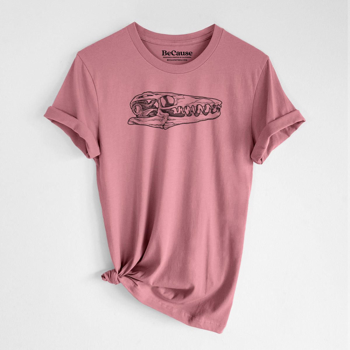 Mauve pink lightweight cotton t-shirt laid flat with the sleeves rolled, printed with a detailed black ink illustration of a Mosasaur skull.