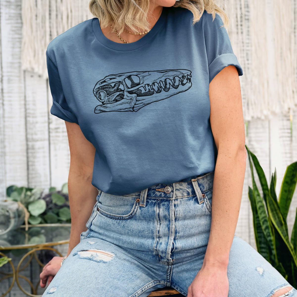 Woman wearing a steel blue lightweight cotton t-shirt printed with a detailed black ink illustration of a Mosasaur skull.