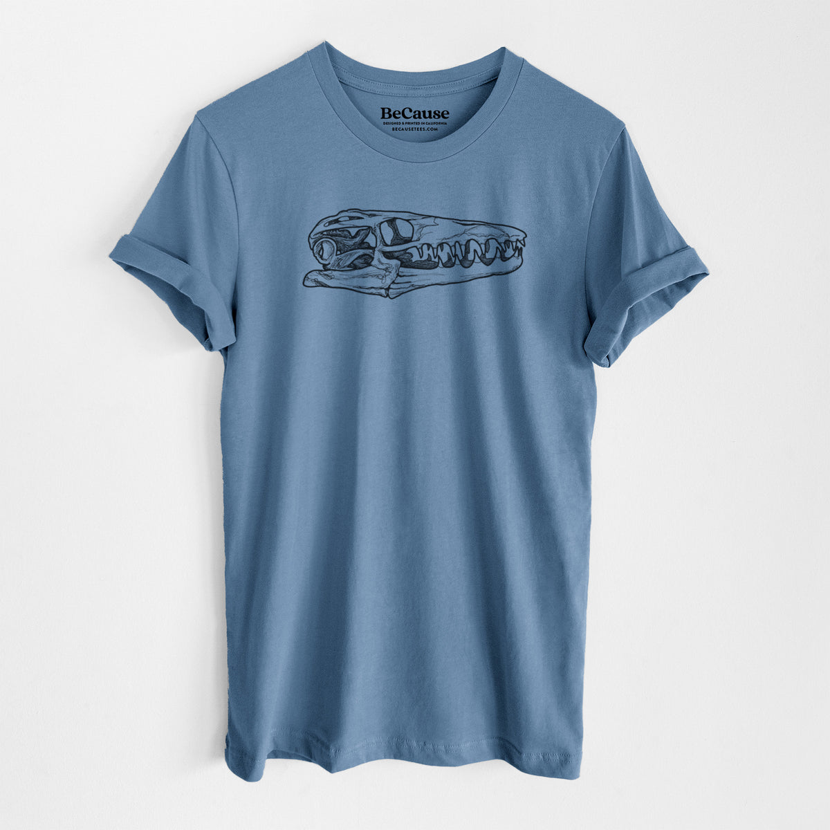 Steel blue lightweight cotton t-shirt laid flat, printed with a detailed black ink illustration of a Mosasaur skull.