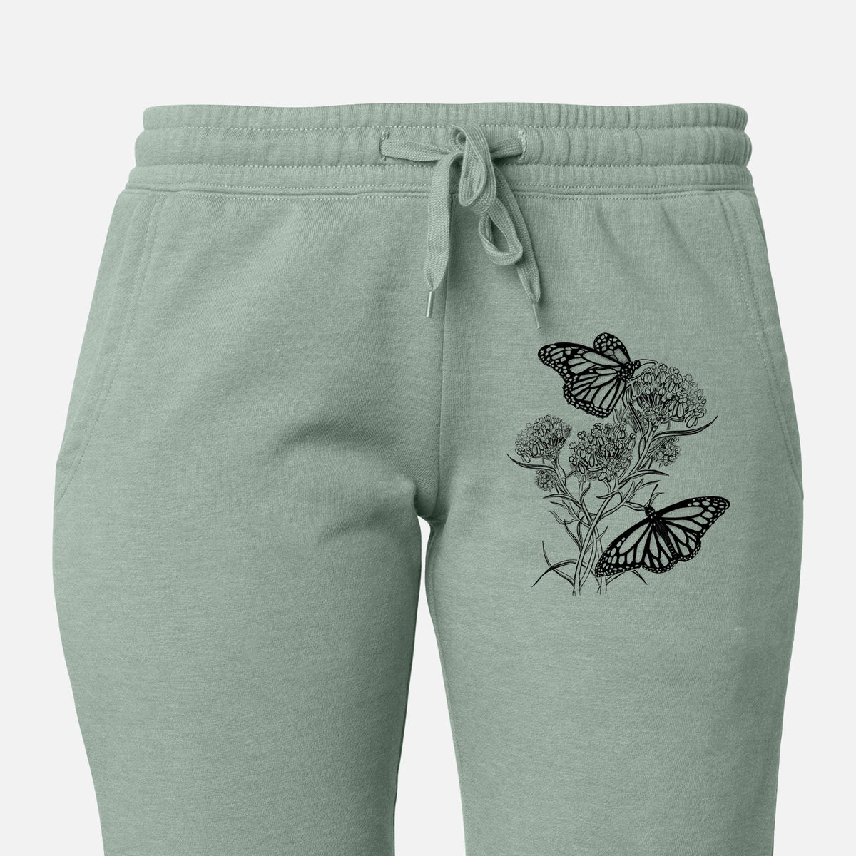 Front of sage green Cali Wave sweatpants, printed with a black ink illustration of two monarch butterflies on flowering milkweed on the leg.