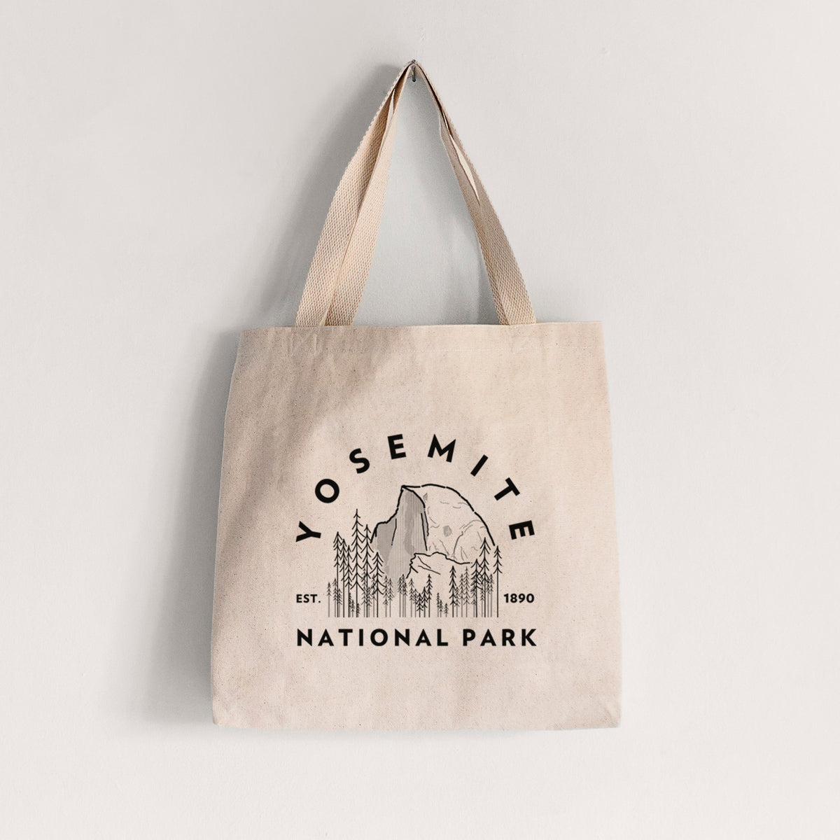 Natural canvas tote bag printed with a round badge of Half Dome and pine trees, with the words Yosemite National Park, Est. 1890.