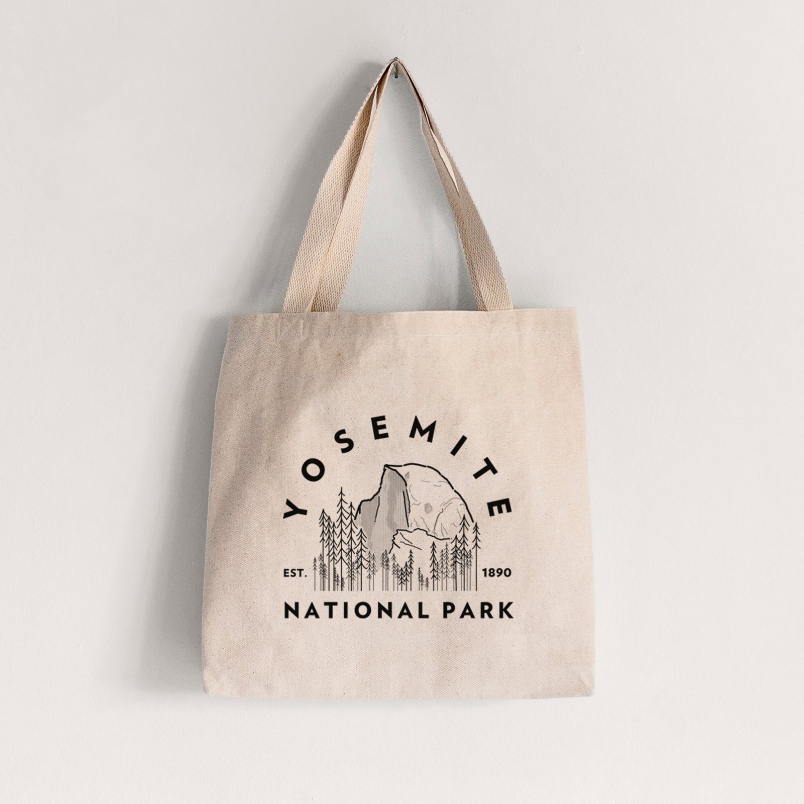 Natural canvas tote bag printed with a round badge of Half Dome and pine trees, with the words Yosemite National Park, Est. 1890.
