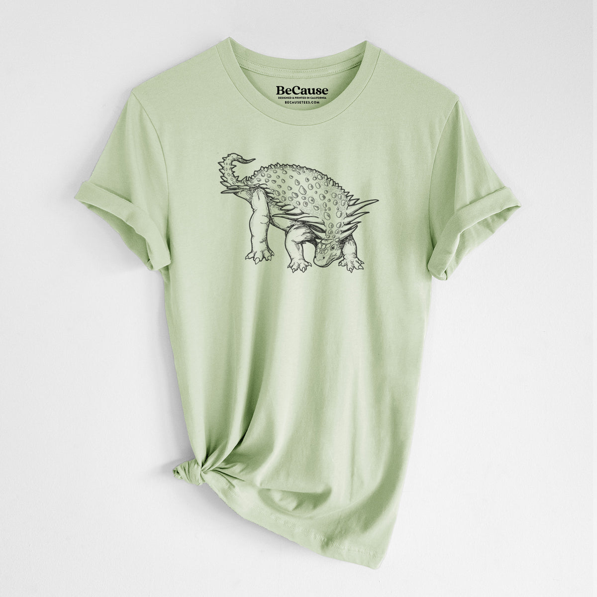 Spring green lightweight cotton t-shirt laid flat with the sleeves rolled, printed with a black ink illustration of an armored Nodosaurus.
