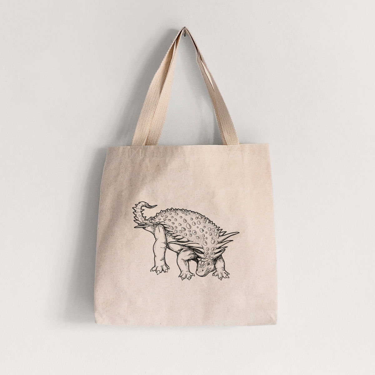 Natural canvas tote bag printed with a black ink illustration of an armored Nodosaurus.