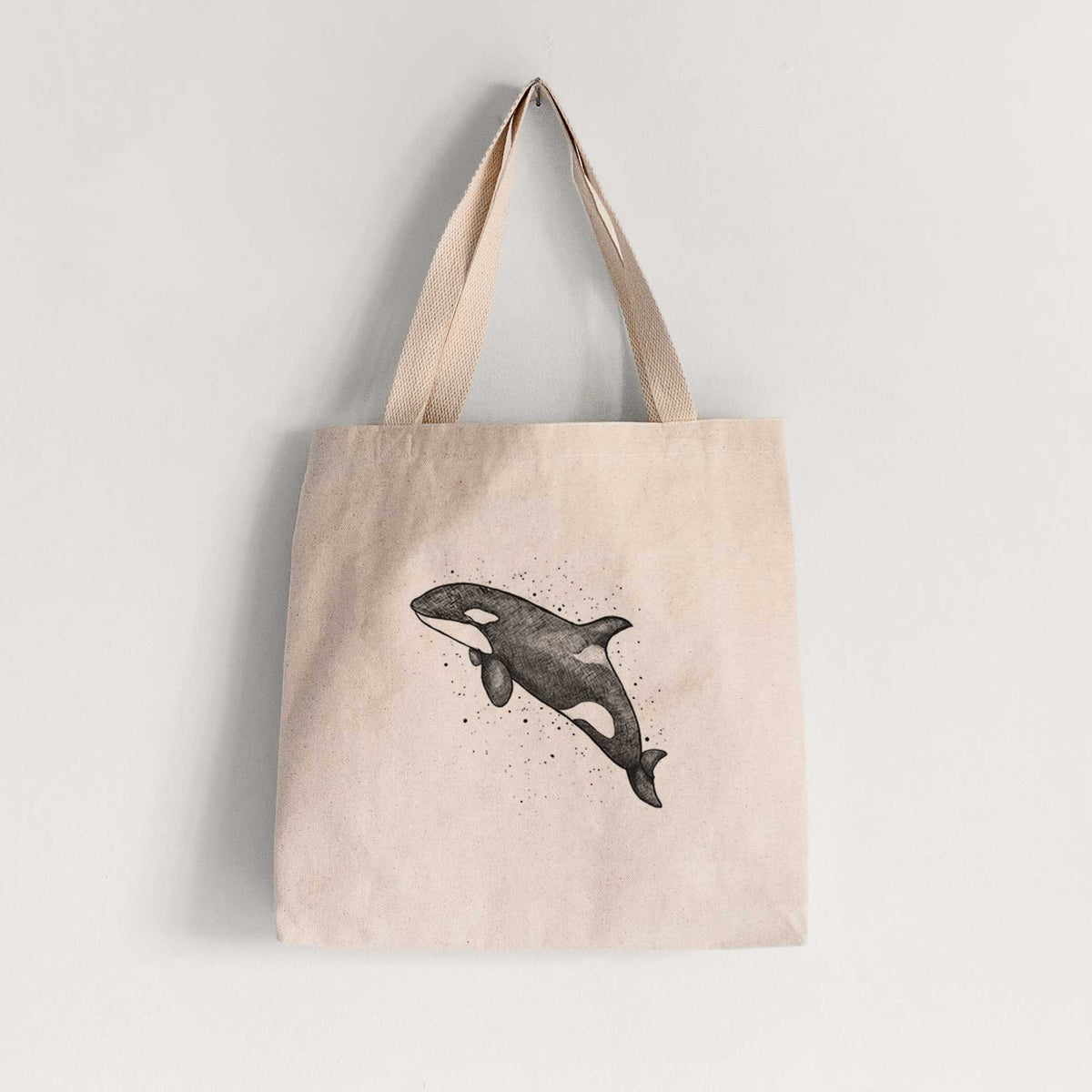 Natural canvas tote bag printed with a black ink illustration of an orca leaping, with ink splatters.