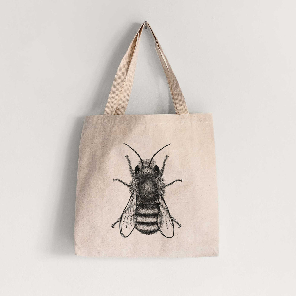 Natural canvas tote bag printed with a detailed black ink illustration of a red mason bee with its wings spread, seen from above.