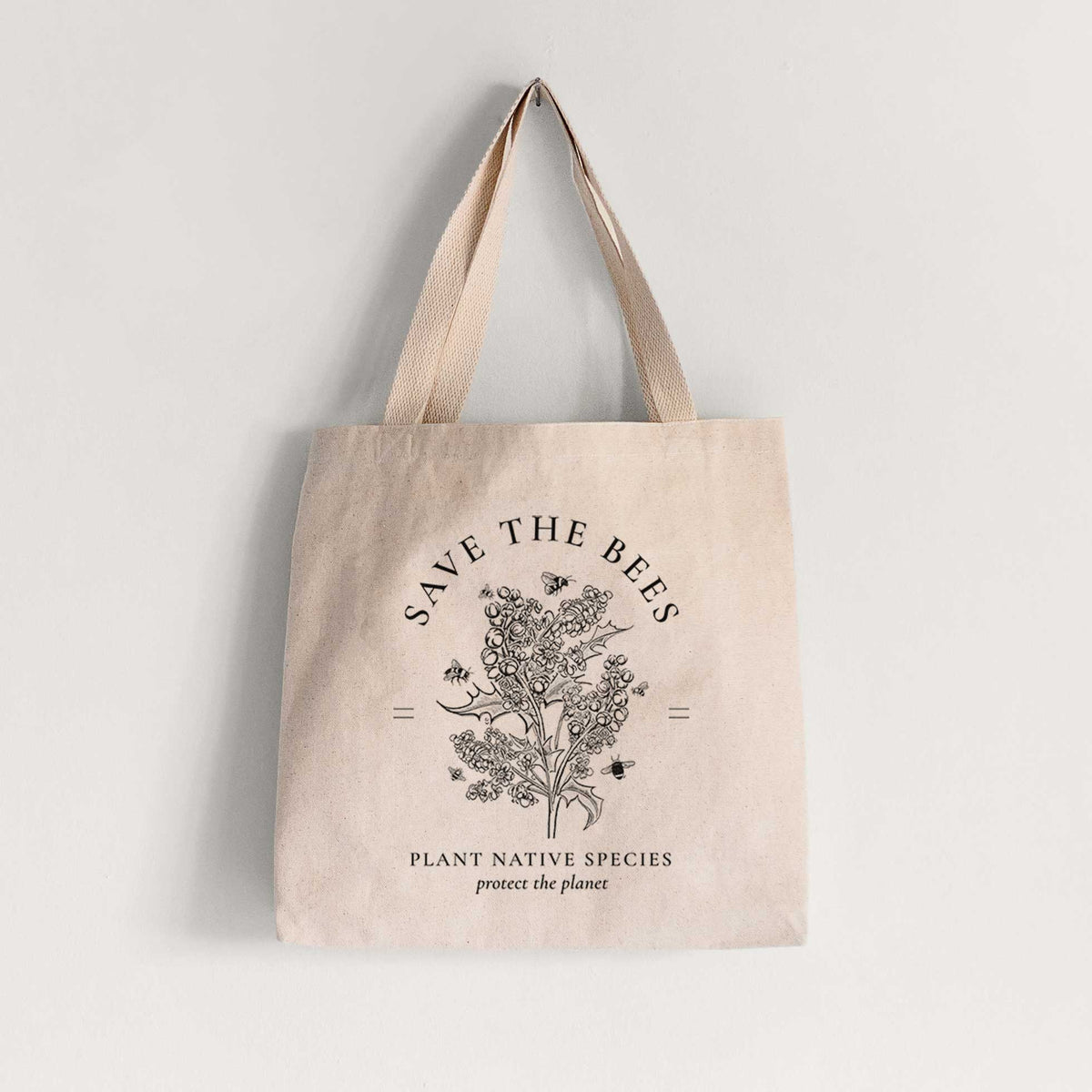 Natural canvas tote bag printed with a black ink wildflower bouquet with bees, framed by the words Save the Bees, Plant Native Species.
