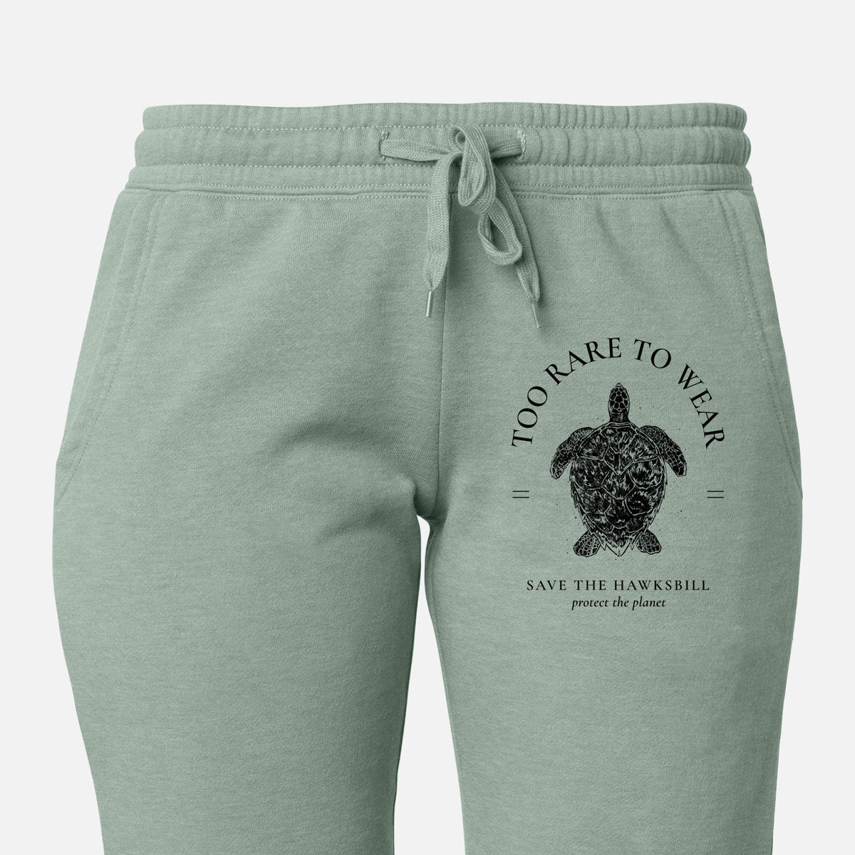 Front of sage green Cali Wave sweatpants, printed with a black ink hawksbill sea turtle framed by the words Too Rare to Wear, Save the Hawksbill on the leg.