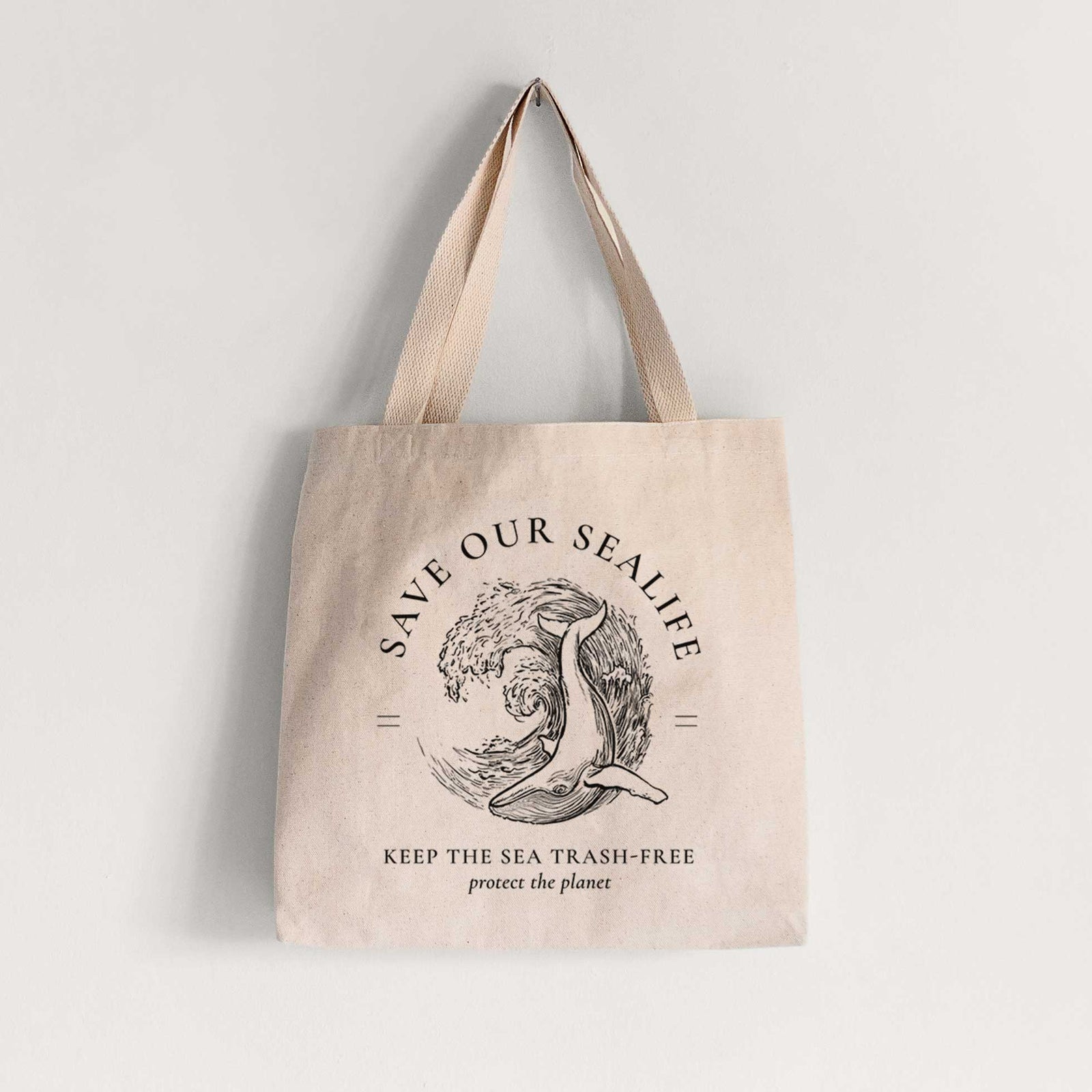 Natural canvas tote bag printed with a black ink whale in an ocean wave framed by the words Save Our Sealife, Keep the Sea Trash-Free.