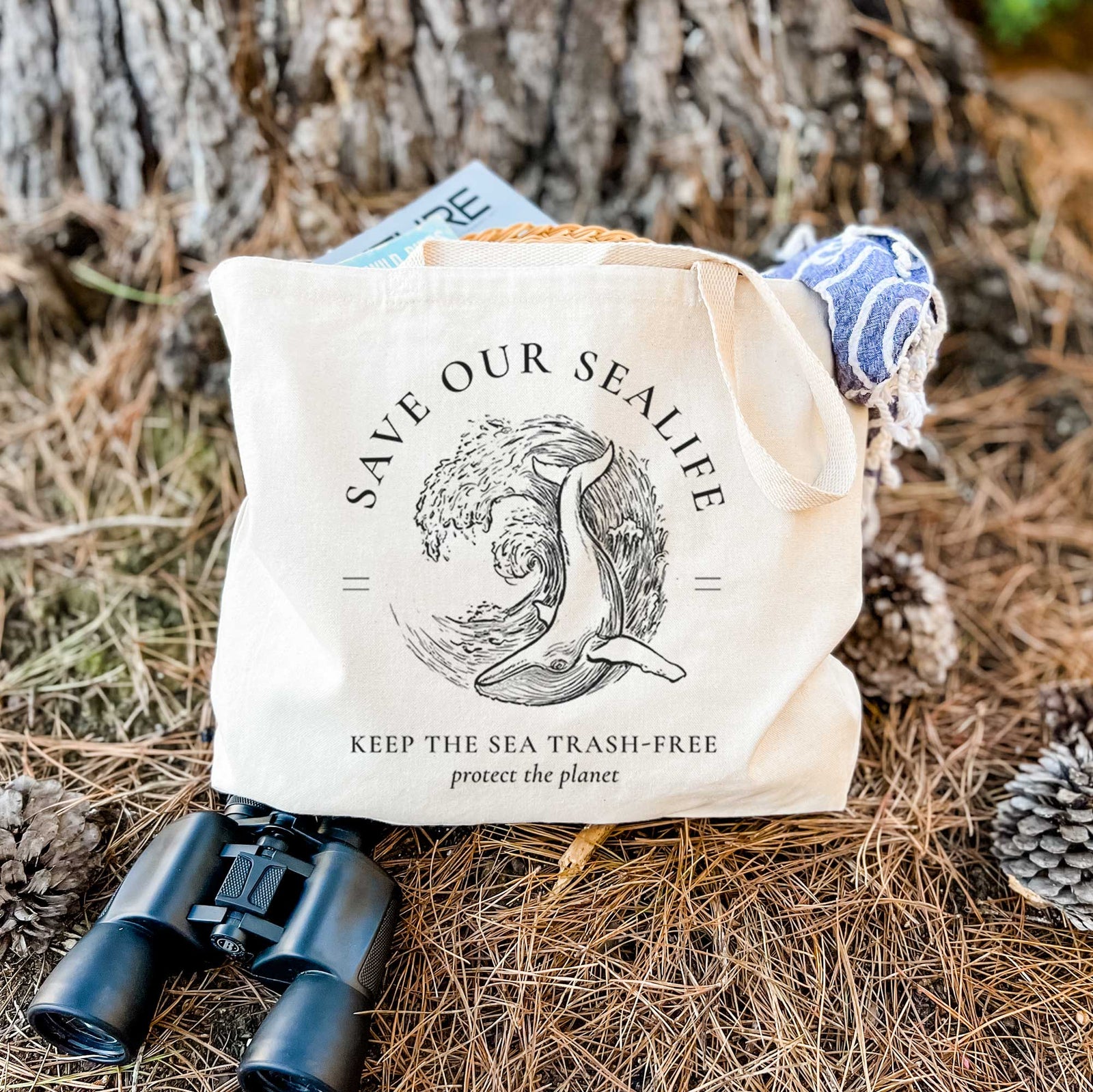 Natural canvas tote bag printed with a black ink whale in an ocean wave framed by the words Save Our Sealife, Keep the Sea Trash-Free.