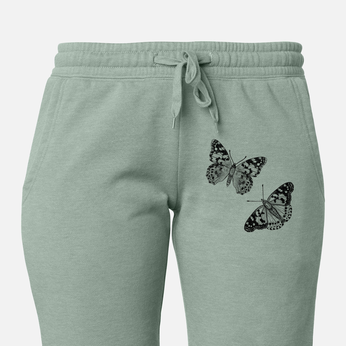 Front of sage green Cali Wave sweatpants, printed with a detailed black ink illustration of two painted lady butterflies on the leg.