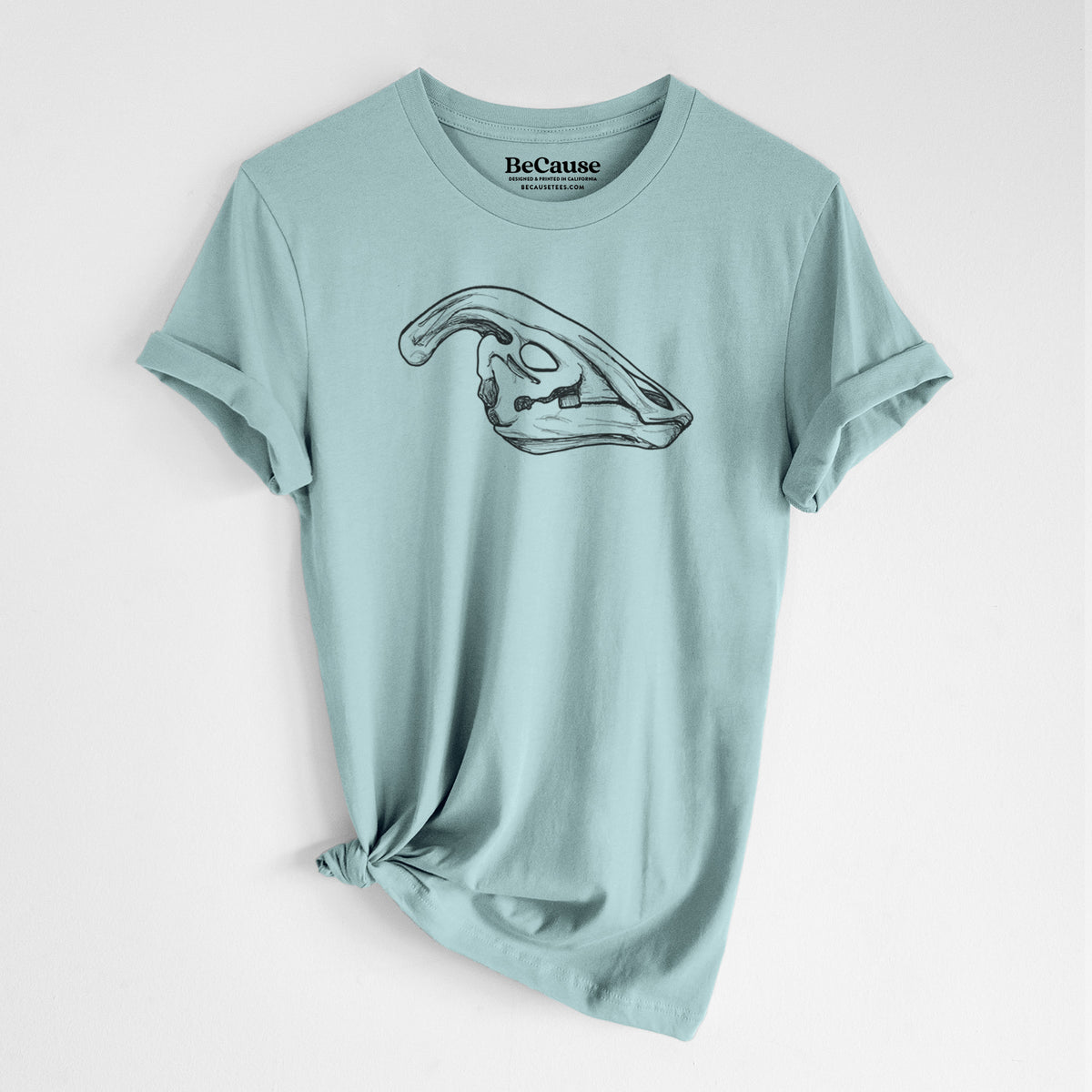 Dusty blue lightweight cotton t-shirt laid flat with the sleeves rolled, printed with a detailed black ink illustration of a crested Parasaurolophus skull.