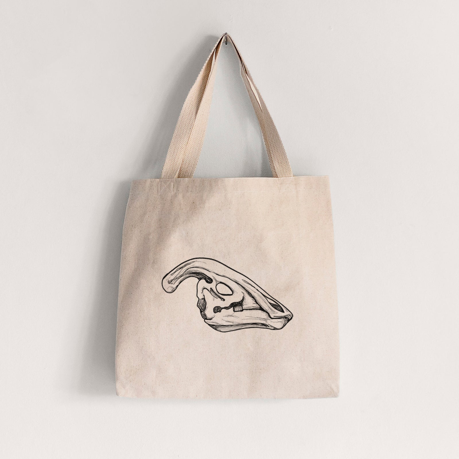 Natural canvas tote bag printed with a detailed black ink illustration of a crested Parasaurolophus skull.
