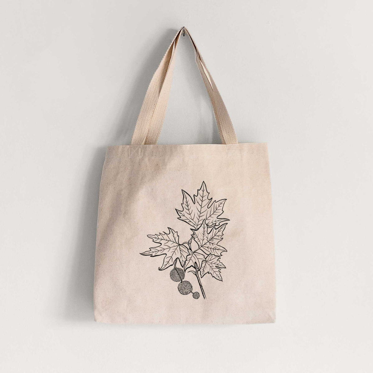 Natural canvas tote bag printed with a black ink illustration of an oriental plane tree branch with lobed leaves and round seed balls.